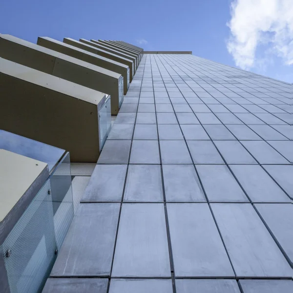 Vertical low angle shot tall building with glass balconies beautiful blue sky scaled 1 600x600